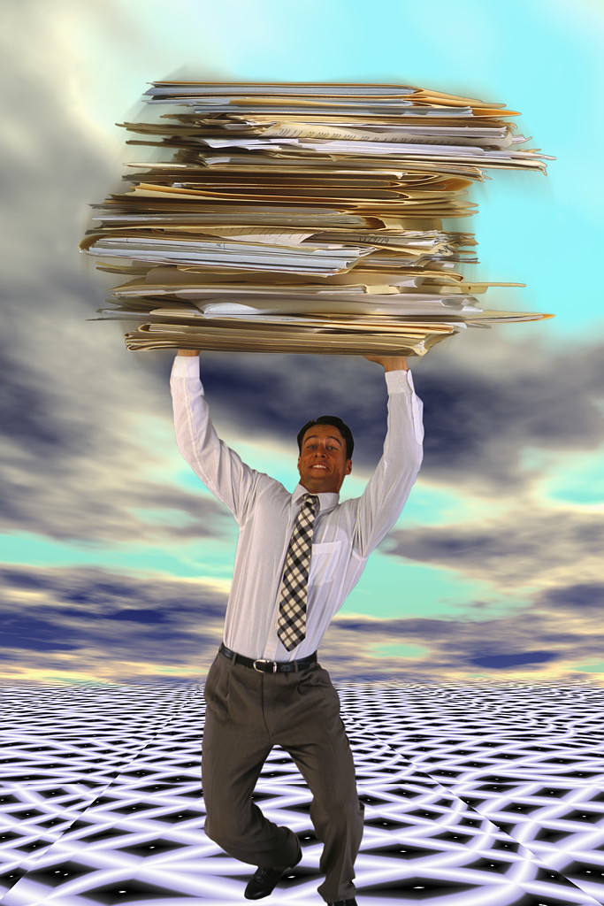 man holding up a big pile of folder and paper