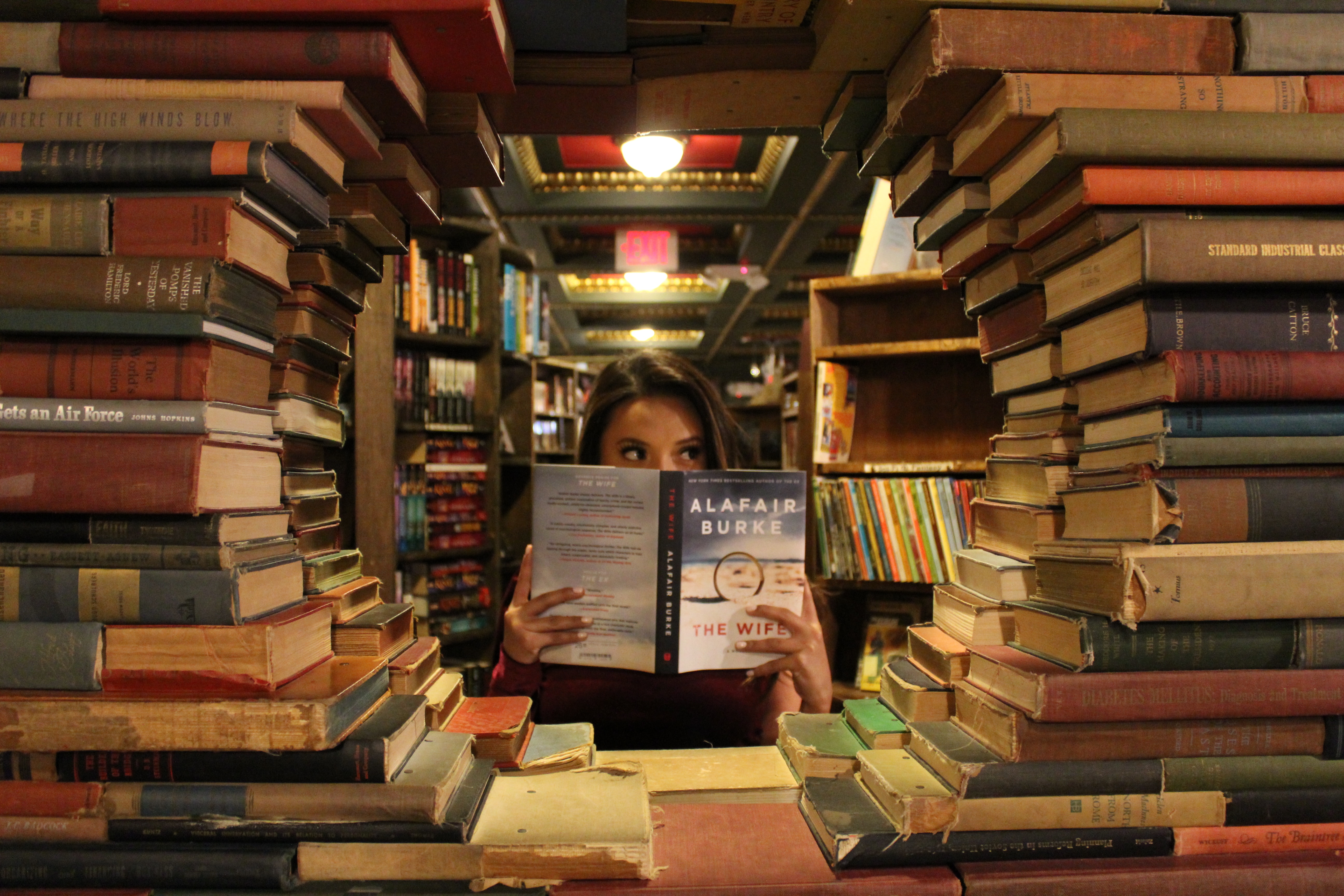 Girl reading book surrounded by books at library - Blueprint Career Development