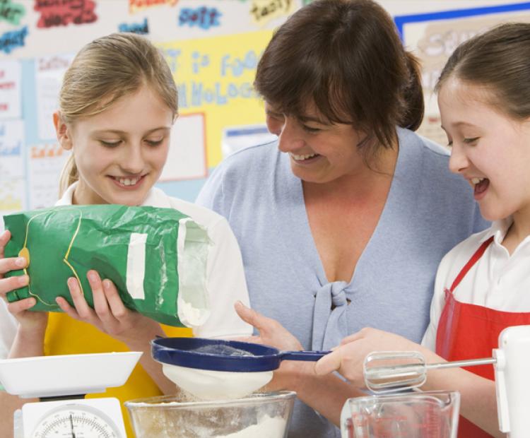 Teacher assisting students in cooking